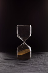 A sandglass, modern hourglass measuring the passing time in a countdown to a deadline, on a dark...