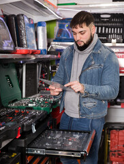 Attentive male is choosing ratchet in tools store