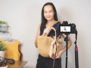 woman  working at home,  using camera  to live or record video selling her woven bag. Indoor,  selective focus. Business and online selling concept.