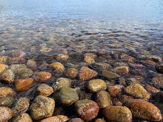 Amazing background; color pebbles when the surf is coming in.  It is a sunny day, the tide is low and the water is clean and clear, so we can see this beautiful picture. 