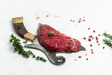 Raw striploin steak with thyme and pepper served on old meat butcher on light background. Top view. copy space