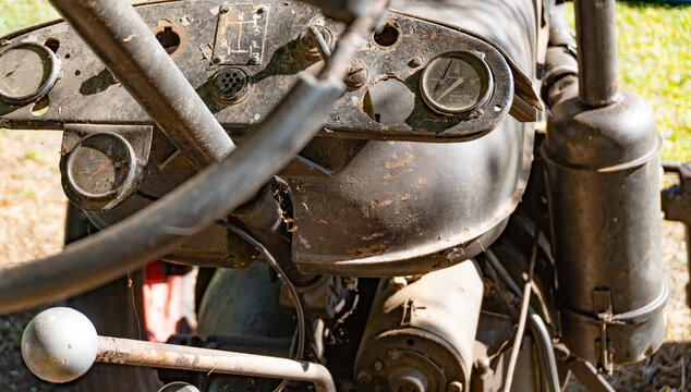 Old, Dashboard and steering wheel of antique Zetor brand tractor from the 50s still in use in the field, red color. Oxide. Close up.
