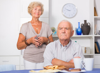 Elderly upset man sitting separately having problems in relationship with spouse