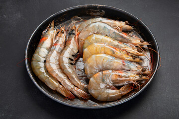 Raw pacific white prawns on dark background. Fresh seafood concept.