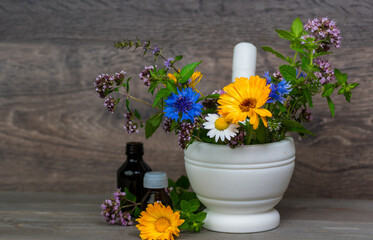 white mortar with fresh medical herbs on wooden table, herbal spa or aromatherapy background