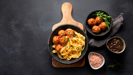 Tagliatelle with meatballs and tomato sauce on dark background. Italian food concept.