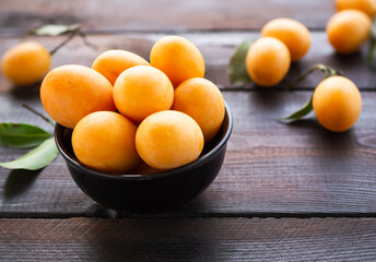 Plum mangos, maprang, marian plum, plango. in black cup on wooden background. tropical fruits in thailand. orange and sweet fruit. snack food for diet good health.