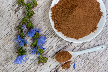 chicory or coffee or cocoa powder on small white plate with fresh little blue flowers