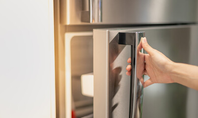 Female hand opening a refrigerator door for find the food and ingredient preparing to cooking in...