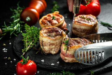 Grilled beef steak by chef hands on black background. filet Mignon beef tenderloin steak covered bacon with spices. top view