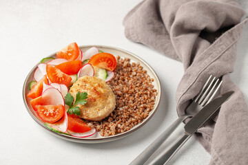 Chicken cutlet with buckwheat porridge and vegetable salad in a plate on the table. Healthy food