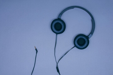 Large black musical headphones with a wire on a gray background.