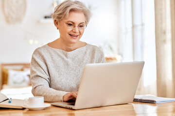 Elderly female freelancer working at laptop