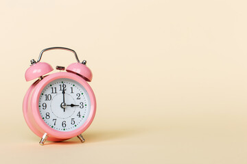 Pink alarm clock on a yellow background. Copy space.