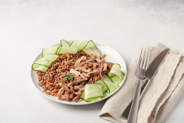 Boiled beef meat, buckwheat and cucumber in a plate on the table. Diet nutrition