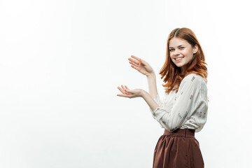 cheerful red-haired woman in a suit gesturing with her hands side view light background