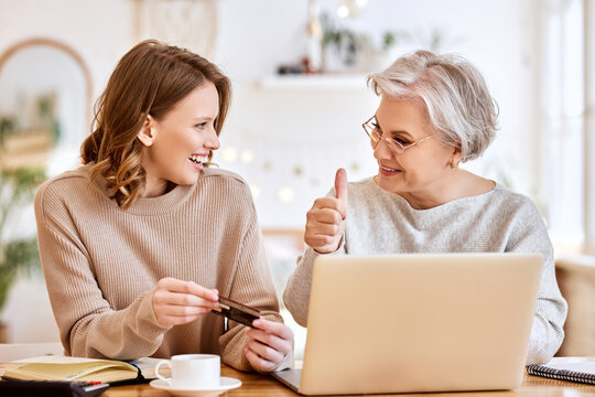 Young woman and senior mother together to make purchases via the Internet to do online shopping