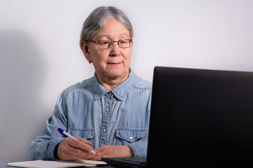Senior business woman with laptop. Elderly woman working on laptop computer, smiling. Isolated over white background