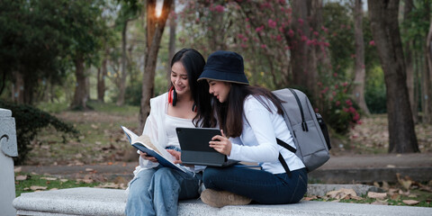 Obraz premium Asian woman traveler with backpack using maps on tablet and sitting in park, travel holiday relaxation concept.