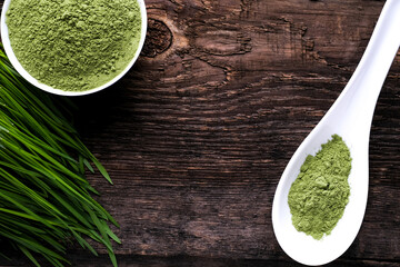 Detox  Green Barley Sprout grass, bowl and a spoon with Powder . Space for Text on wooden background