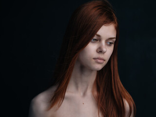 Portrait of a woman with red hair on a black background naked shoulders model