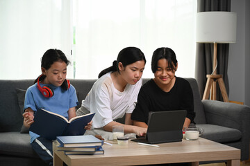 Three asian girl sitting on sofa and using digital tablet.