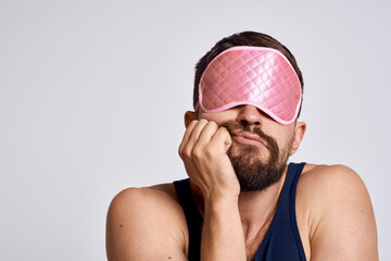 A man in a black t-shirt in the morning sleep mask close-up gray background