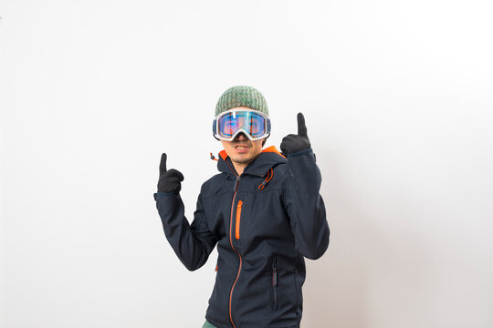 Asian man in winter coat, goggles and glove dressing for snowboarder on white background.