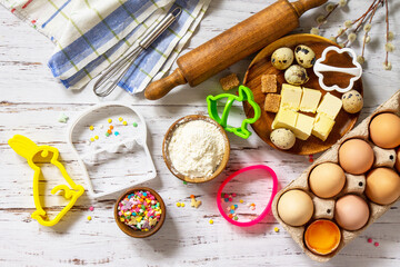 Baking background. Ingredients for Easter festive baking - flour, brown sugar, eggs, butter, confetti on rustic kitchen table.