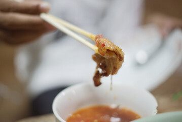 Wooden chopsticks tong barbecue pork and sauce on an Electric grilled aluminum pan  with soup barbecue party on a wooden table