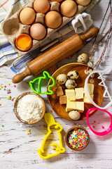 Baking or cooking background frame. Ingredients, kitchen items for Easter festive baking. Kitchen utensils, flour, brown sugar, eggs, butter, confetti on rustic kitchen table. Flat lay. Top view.