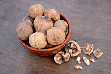 bunch the healthy brown walnut in the wooden bowl on the brown background.