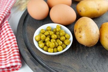 Peas, potatoes and eggs on a wooden board, close-up