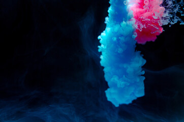 Multi-colored paints in water. Ink swirls underwater. A cloud of collision of bright ink on a black background. Colorful abstract explosion of smoke. Abstract background