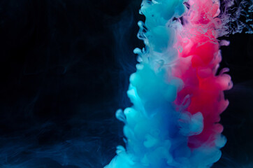 Multi-colored paints in water. Ink swirls underwater. A cloud of collision of bright ink on a black background. Colorful abstract explosion of smoke. Abstract background