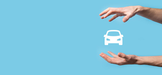 Male hand holding car auto icon on blue background. Wide banner composition.Car automobile insurance and collision damage waiver concepts