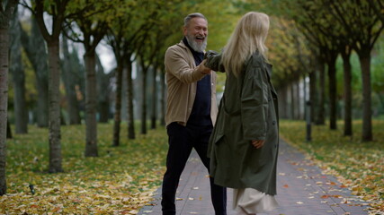 Wide shot of exciting romantic couple having fun in autumn park.