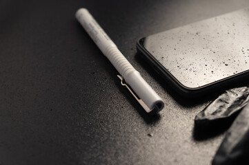Pen with smartphone in drops of water on black background