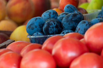 Plums, tomatoes and peaches with apples on the window on the counter. Close-up. A small depth of field.