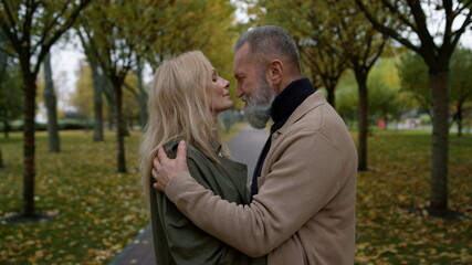 Beautiful woman and bearded man standing in park. Cheerful mature couple.