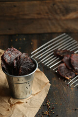 Homemade beef jerky seasoned with garlic, onion, pepper and salt. Jerky in a bucket on a wooden...