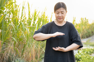 Asian old woman working out with practicing taichi breathing technique, traditional fitness style