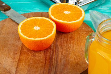 Glass of orange juice and cut oranges on table