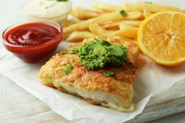Tasty fried fish and chips on white board, close up