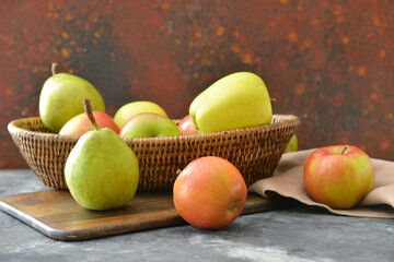 Basket with tasty apple and pear fruits on table