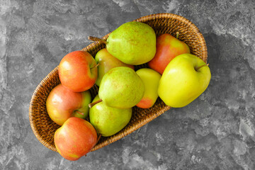 Basket with tasty apple and pear fruits on dark background