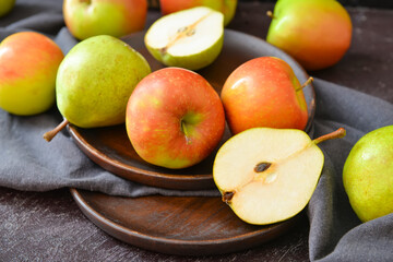 Plates with tasty apple and pear fruits on dark background