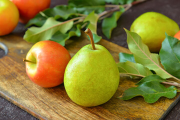 Board with tasty apple and pear fruits on dark background