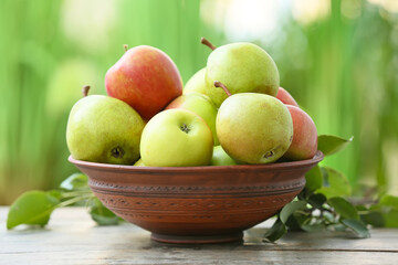 Bowl with tasty apple and pear fruits on table outdoors