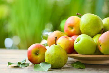 Plate with tasty apple and pear fruits on table outdoors